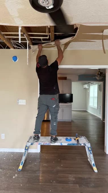 Worker removing ceiling drywall above a doorway at the Georgetown home.